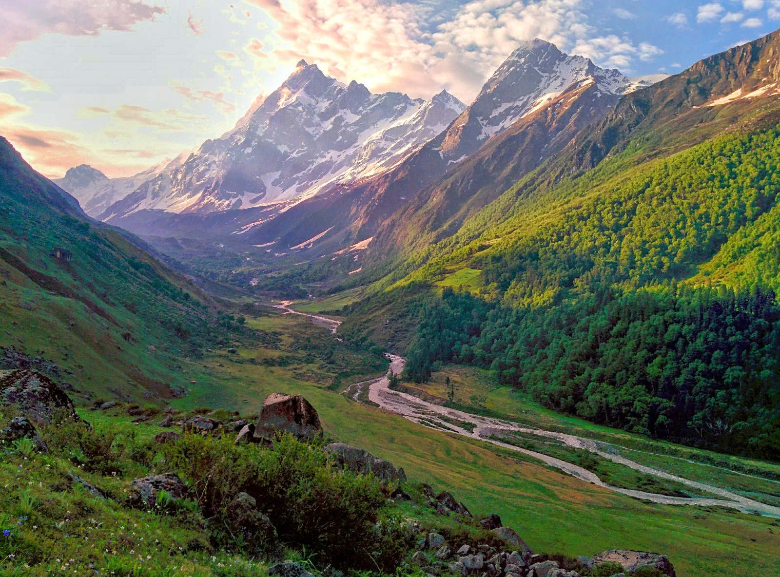 Green Har Ki Dun valley with the river winding below snow-capped Himalayan peaks at sunrise
