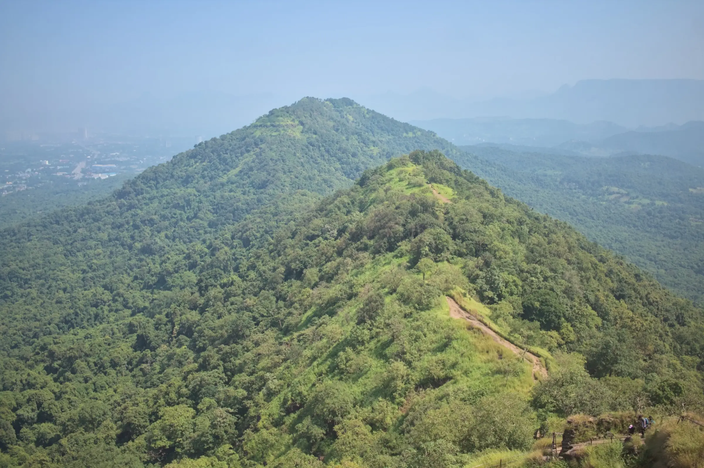 Forested hills of Karnala Bird Sanctuary seen from the fort, with a trail along the green ridge
