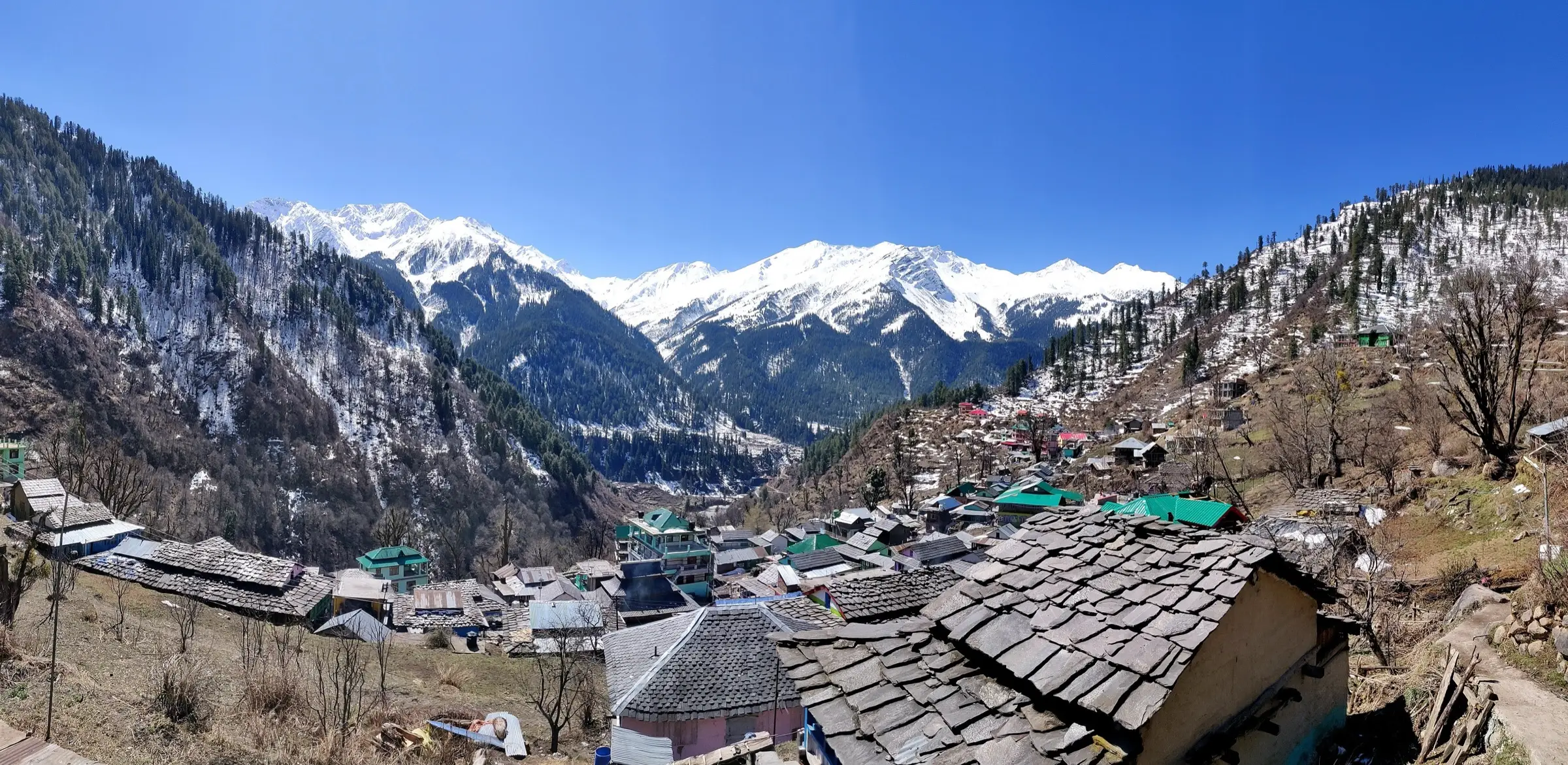 Slate-roofed houses of Tosh village in spring, with snow peaks at the head of the valley behind