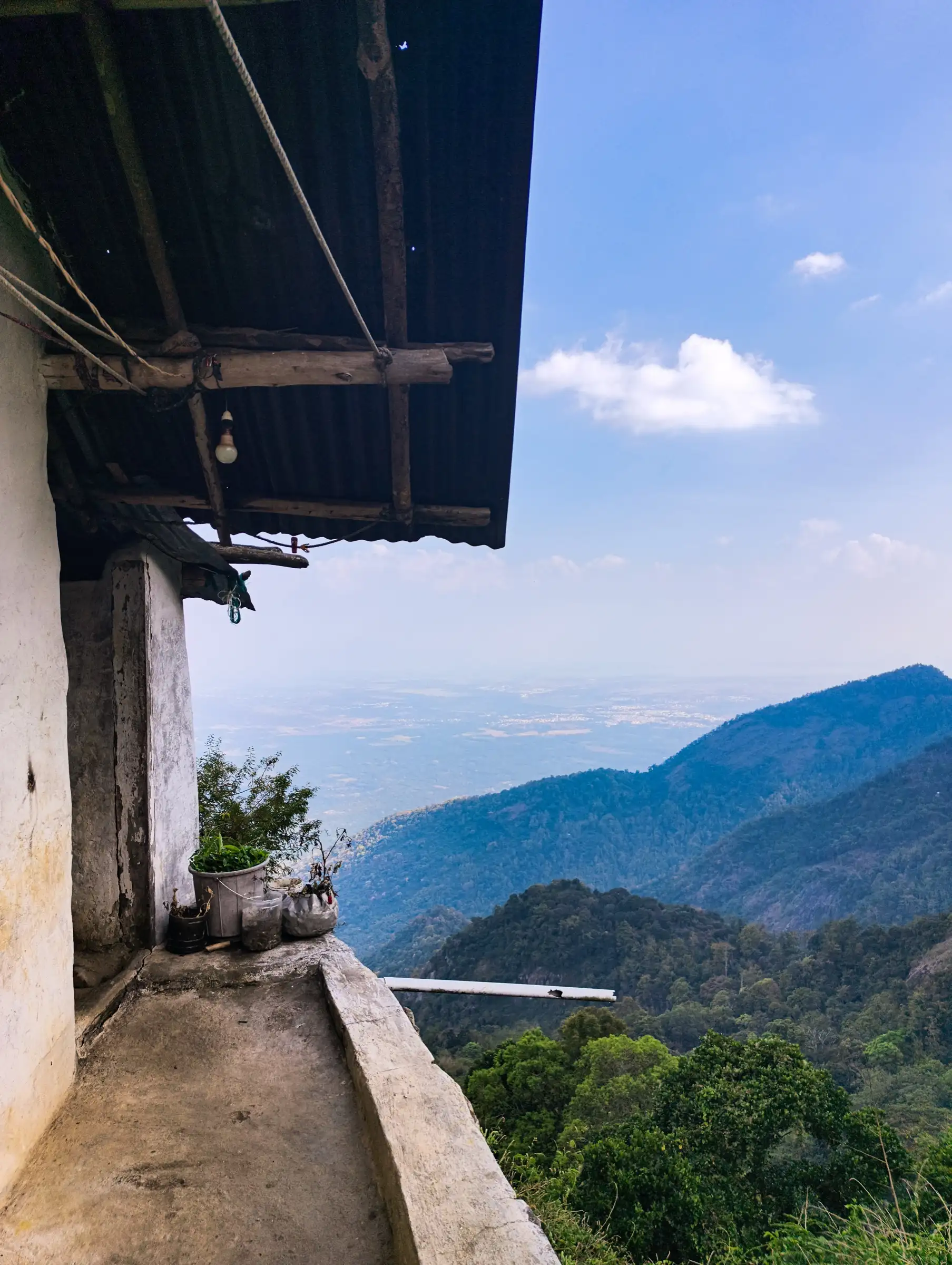View from a house veranda in Vellagavi village over forested ridges and the hazy plains below