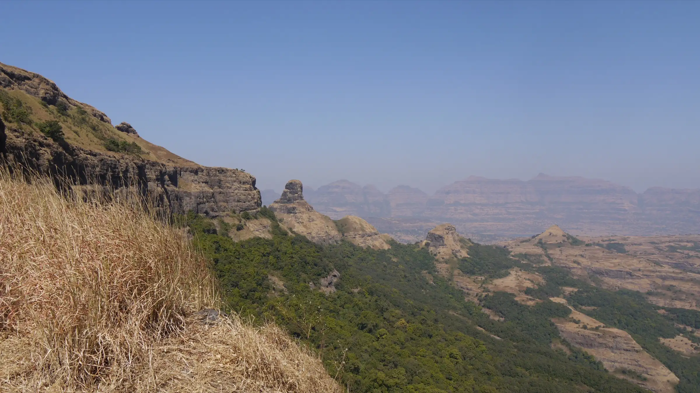 Dry grass, forested slopes and rock pinnacles looking north from Ratangad, about 2 km from Katrabai (surrounding area, not the trek itself)