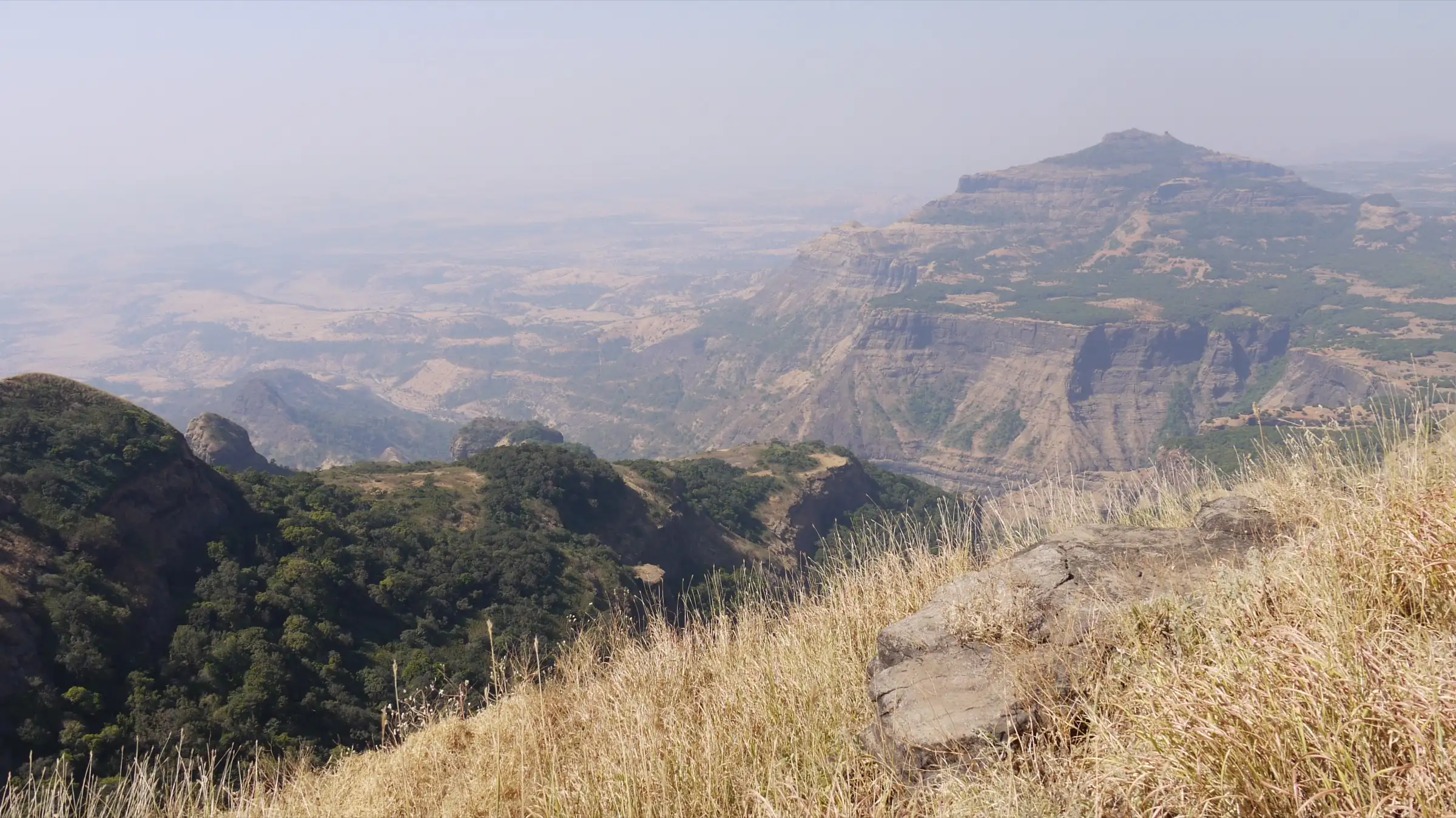 Hazy valleys and a flat-topped mountain seen looking north-west from Ratangad, about 4 km from Ajobagad (surrounding area, not the trek itself)