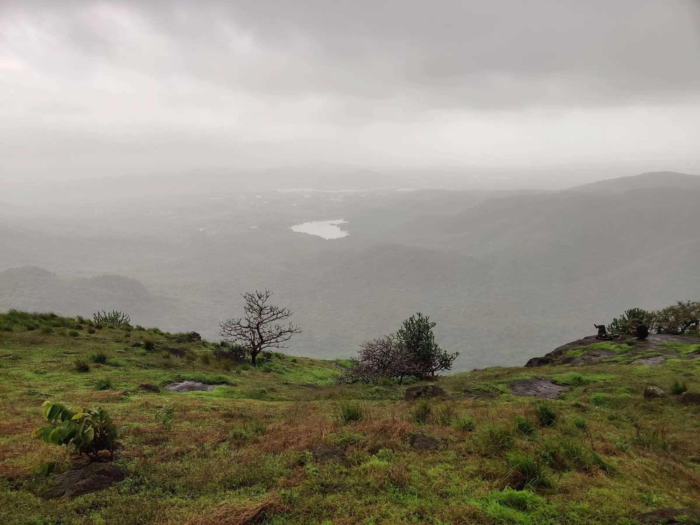 Misty monsoon view from the grassy top of Tandulwadi Fort towards Zanzorli lake in the plain below