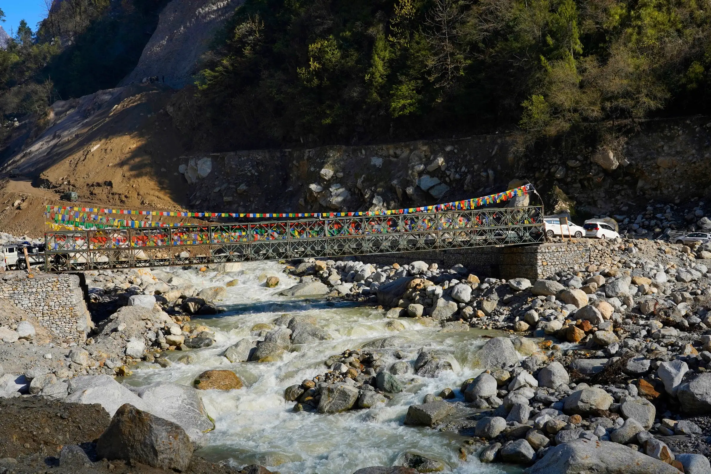 A steel bridge hung with prayer flags over the rocky Zemu Chu river near Lachen, the start of the walk up the valley